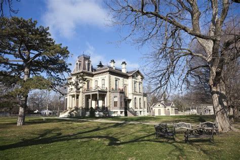 An Old Mansion With Trees And Benches In The Foreground