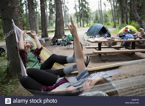 Teenage Girl Friends Relaxing Laying In Hammocks At Outdoor School