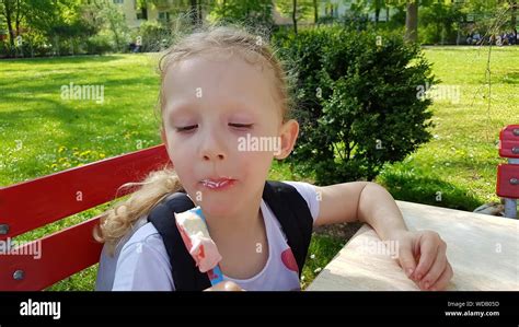 Girl Holding Ice Cream While Sitting On Bench At Park Stock Photo Alamy