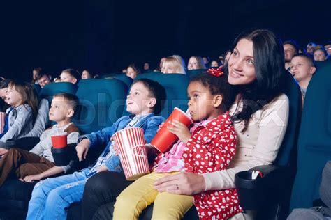 sideview of mother and daughter watching movie in the cinema stock image colourbox