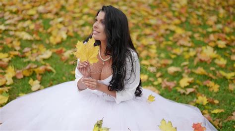 sensual bride in wedding day in autumn busty woman in white dress is sitting on grass in park