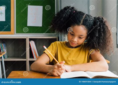 African American School Girl Sitting In School Writing In Note Book