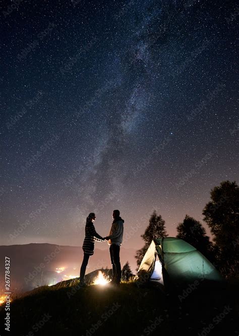 Silhouette Of Happy Romantic Couple Tourists Standing At Campfire Near