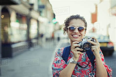 Portrait Smiling Young Female Tourist In Sunglasses Photographing With