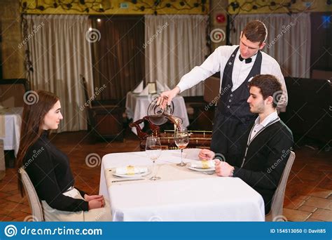 Waiter Pouring Red Wine In A Glass At A Restaurant Table Stock Photo