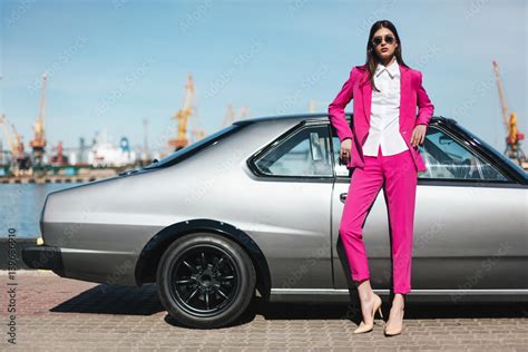 Fashion Girl Standing Next To A Retro Sport Car On The Sun Stylish