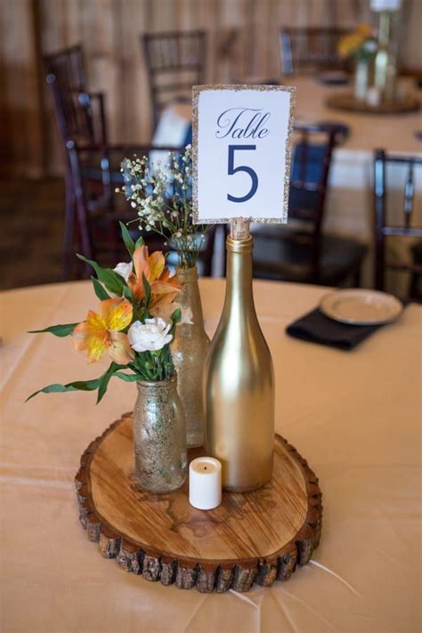 Wedding Reception Centrepiece On Wood Round With Gold Wine Bottle For