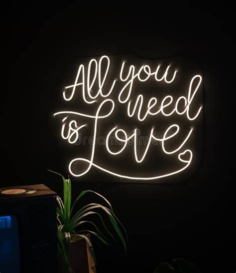 Neon Sign Inscription All You Need Is Love On A Dark Background Stock