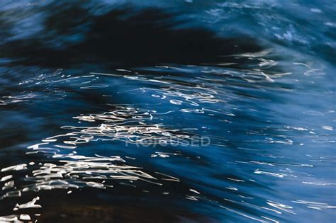 Abstract Close Up Of Flowing River Water With Light Reflection On