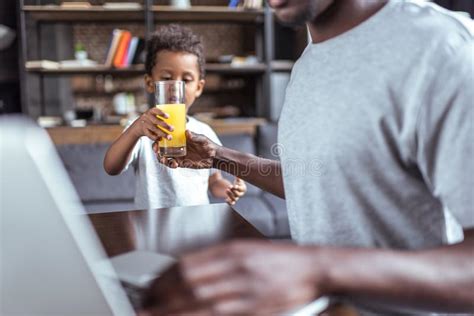 Son Giving Orange Juice To Father Stock Photo Image Of Afro