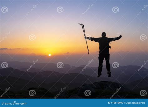 Hiker Standing On Top Of A Mountain With Raised Hands And Enjoying