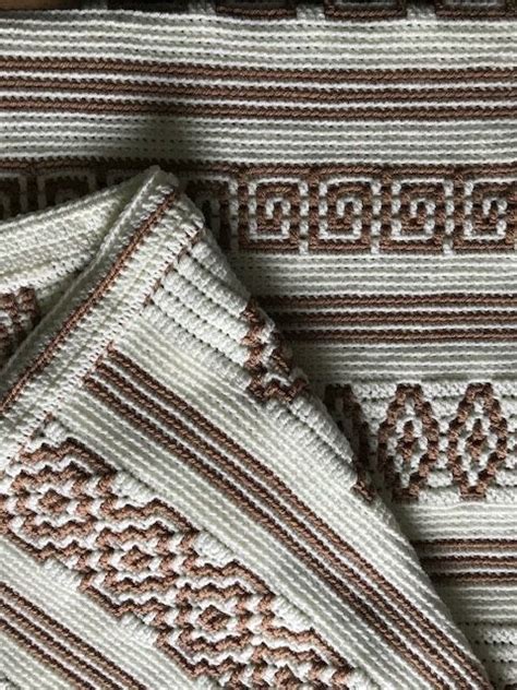 Two Brown And White Knitted Blankets Laying On Top Of Each Other