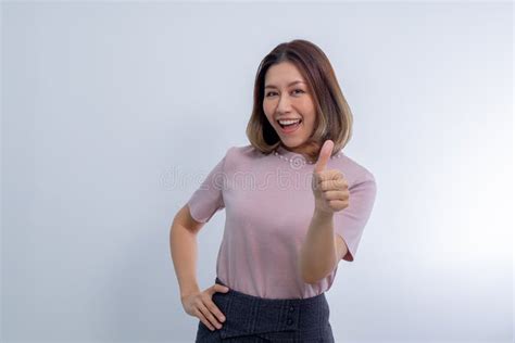 asian woman showing thumb up in approval recommending smiling and looking confident stock