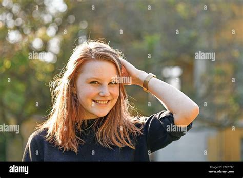 Young Girl With Reddish Hair And Freckles Stands Outdoors And Smiles At