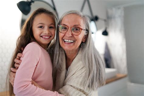 Senior Grandmother And Granddaughter Standing Indoors In Bathroom