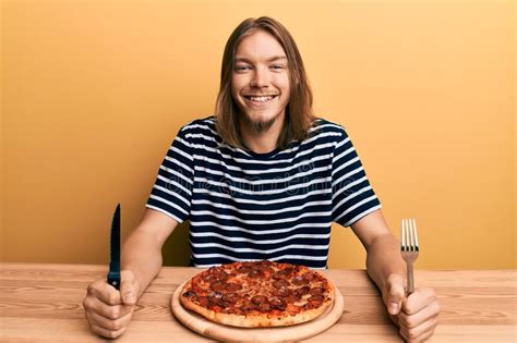 Handsome Caucasian Man With Long Hair Eating Tasty Pepperoni Pizza