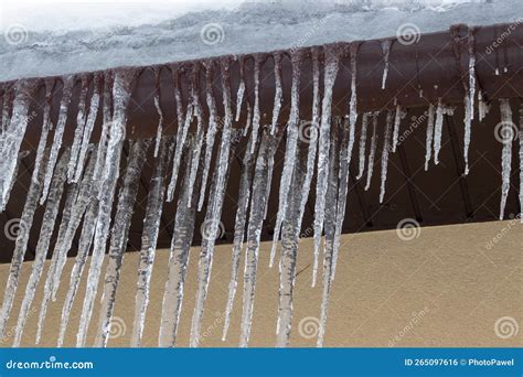Big Icicles On The Roof Of A Townhouse Roof Of Home Covered With