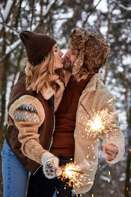 Premium Photo Couple Love Story In Snow Forest Kissing And Holding Sparklers Couple In Winter