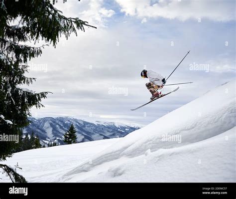 Side View Of Male Skier Making Jump While Sliding Down Snow Covered