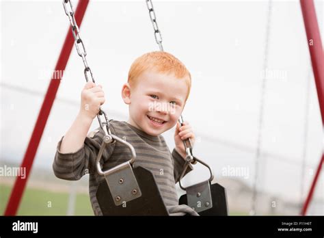 Caucasian Boy Sitting On Playground Swing Stock Photo Alamy