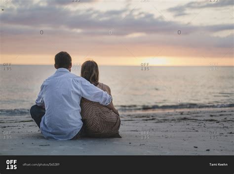 Couple Sitting On The Beach Watching The Sunset Stock Photo Offset
