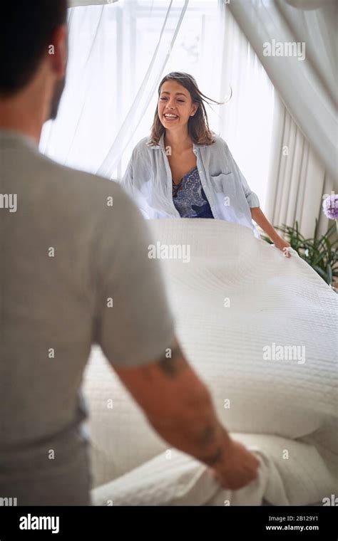 Young Couple Spreading Sheets In The Bedroom With Joy Smiling Bedroom