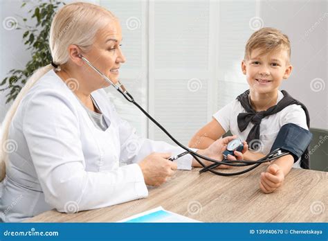 Little Boy Visiting Doctor In Hospital Measuring Blood Pressure Stock