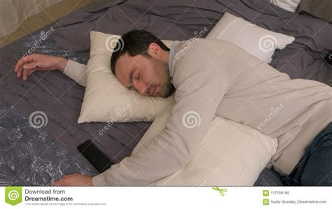 Tired Young Man Lies On Bed And Falls Asleep After Hard Workday Stock