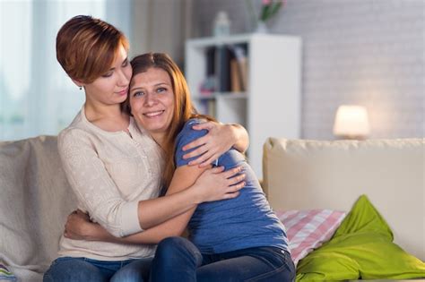 pareja homosexual de mujeres lesbianas en casa en el sofá abrazándose y