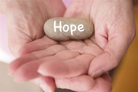 Closeup Of Womans Hands Holding Stone With The Word Hope Stock Photo