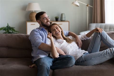 Cheerful Dreamy Married Couple Enjoying Leisure On Sofa Stock Image