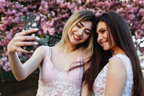 Free Photo Two Girls Take Selfie Before A Beautiful Sakura Tree In The Park