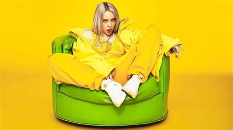 Billie Eilish Is Wearing Yellow Dress And Chains On Neck Standing In