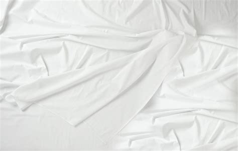 An Unmade Bed With White Sheets And Pillows