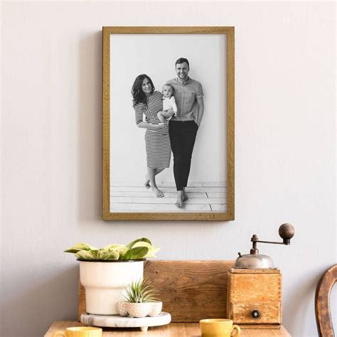 A Man And Woman Standing Next To Each Other In Front Of A Framed Photo