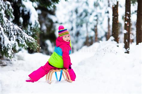 Child Playing In Snow On Sleigh In Winter Park Stock Image