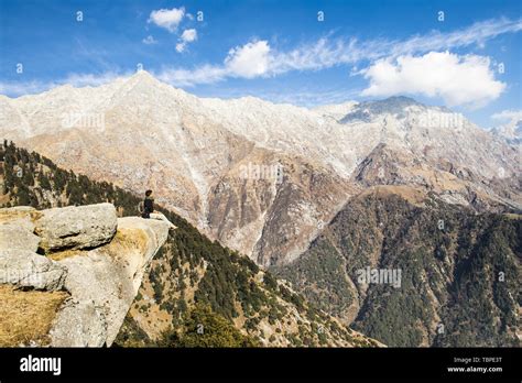 A Tourist Is Sitting On A Cliff Enjoying The Beautiful View Of