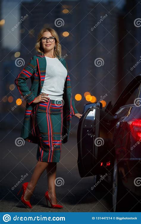 Image Of Blonde Woman In Checkered Suit Standing Next To Black Car