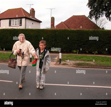 Elderly Lady Being Helped Across The Road By Young Boy Stock Photo Alamy