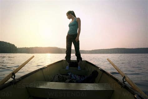 Full Length Of Woman Standing On Boat Against Sky During Sunset Stock Photo