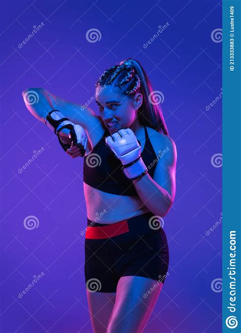 Athletic Female Mma Fighter Training Over Blue Pink Background In Neon
