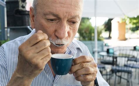 Elderly Man Drinking Espresso Coffee At An Outdoor Cafe Stock Photo