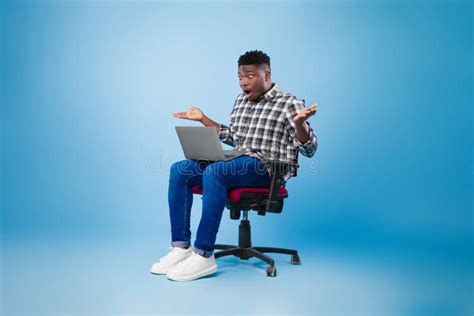 Shocked Millennial Black Man Sitting On Chair With Laptop Surprised