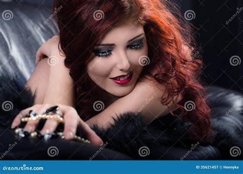 Glamorous Redhead Woman Playing With Pearls On Leather Couch Stock