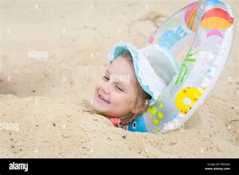Four Year Girl Buried In The Sand On The Beach With His Head Planted