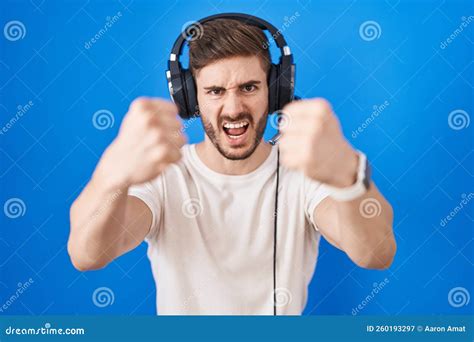 Hispanic Man With Beard Listening To Music Wearing Headphones Angry And