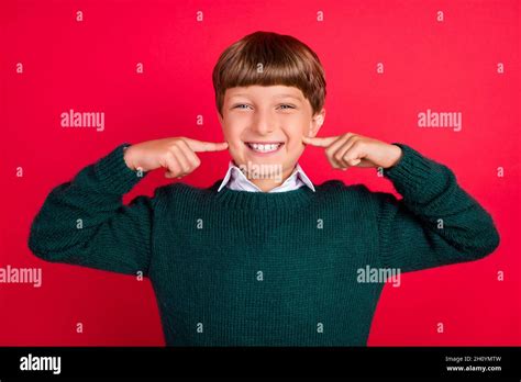 Foto de niño engañando colegial vestido verde suéter dedos mejillas