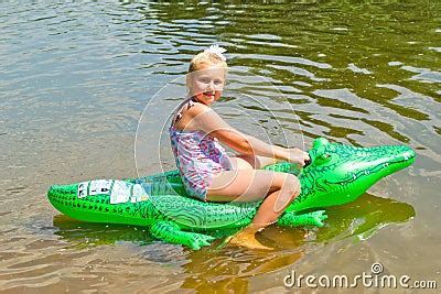Girl Swimming In The River With Inflatable Crocodile Stock Photo