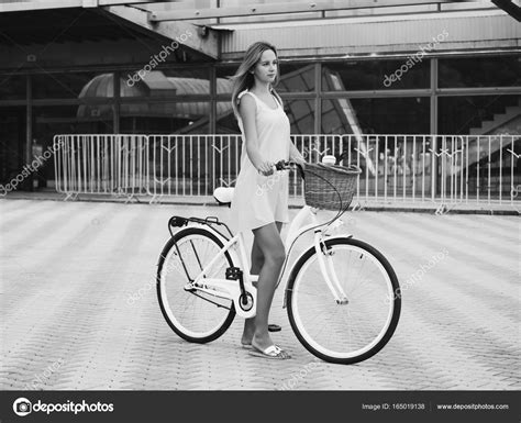 outdoor fashion portrait of elegant blonde lady riding her hipster retro bike in vintage stylish