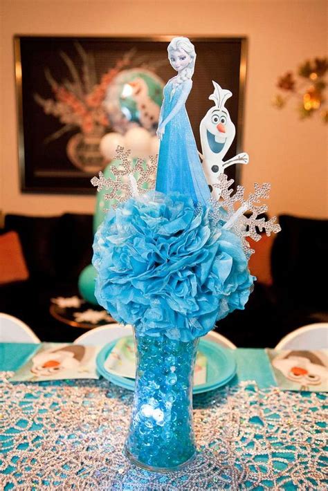 A Frozen Princess Centerpiece Is Displayed In A Vase On A Table With